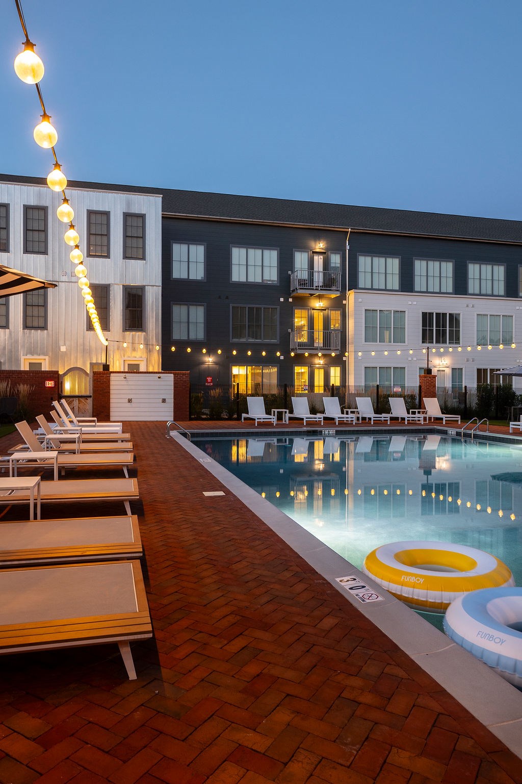 A pool with chairs and a building in the background.