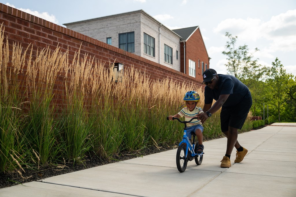A man is teaching a young boy how to ride a bike.