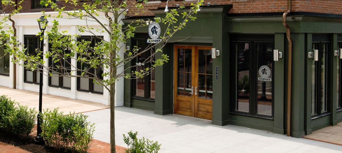 the front of a restaurant with green walls and wooden doors