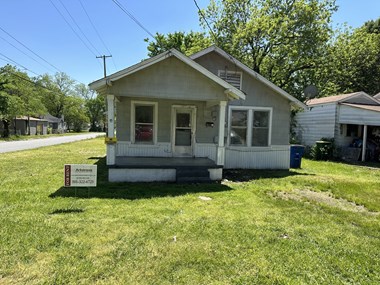 a small white house with a ``for sale' sign in front of it