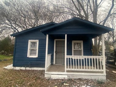 a small blue house with a white porch