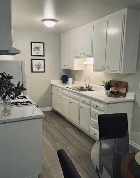 A kitchen with white cabinets and a black chair.