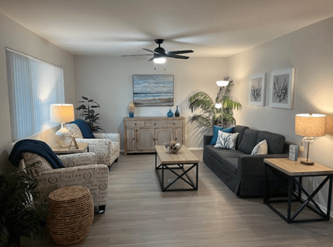 A living room with a ceiling fan and a painting on the wall.
