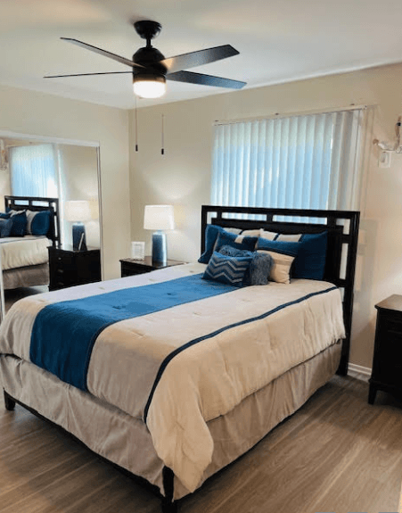A bedroom with a large bed and a ceiling fan.