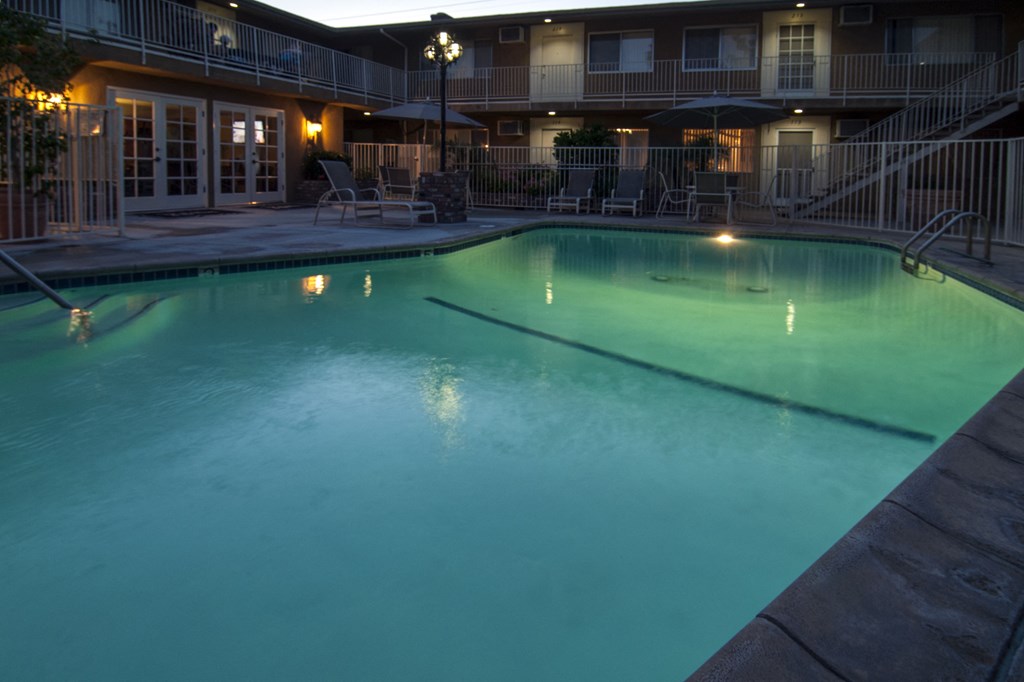 a large pool at night with a hotel in the background
