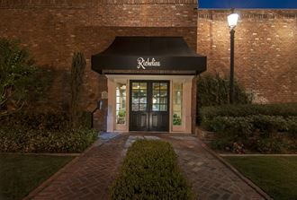 a resident advising office at night with a black awning and a brick path to the