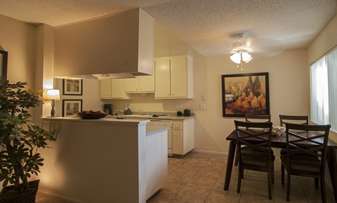 an open kitchen and dining area with a dining table and chairs and a white counter