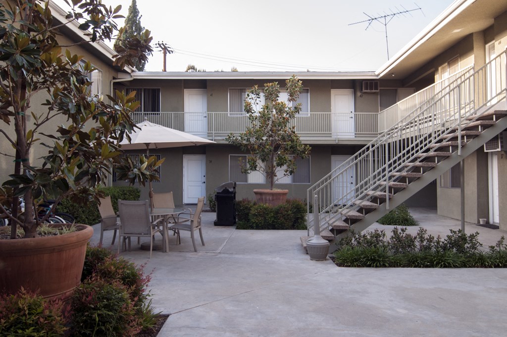 a patio with a table and chairs in front of a building