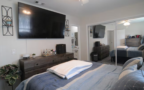 A bedroom with a large bed and a flat screen TV mounted on the wall.