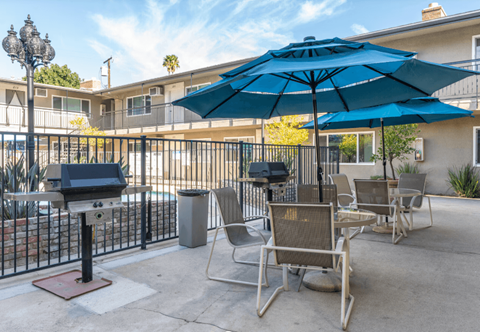 A patio with chairs and an umbrella is in front of a building.