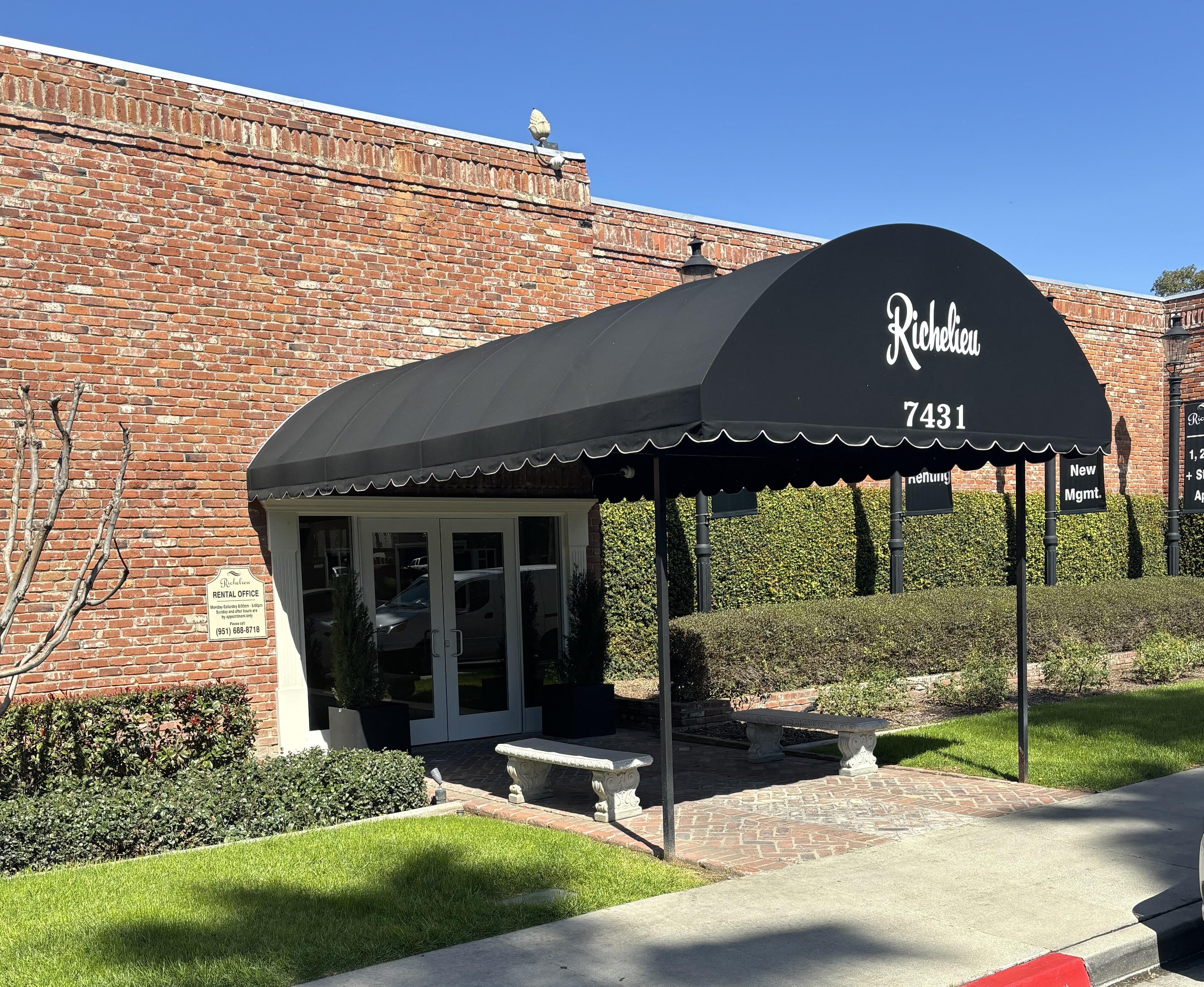 awning in front of a brick building with a bench
