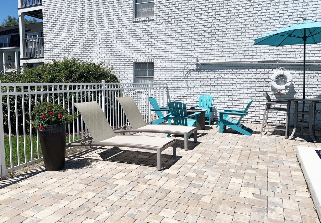 a patio with chairs and an umbrella on a sunny day