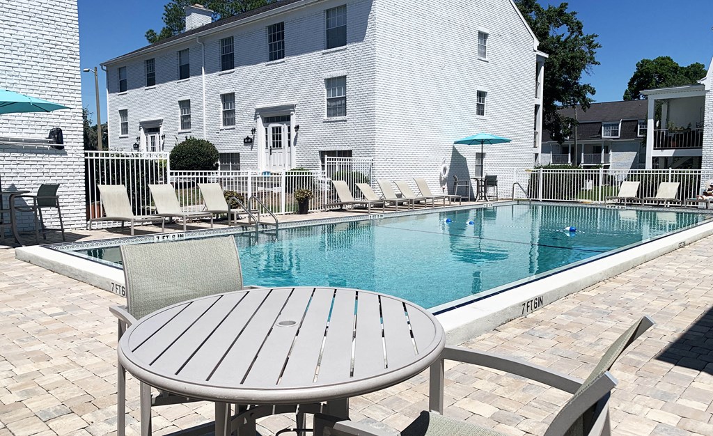 a patio with a table and chairs next to a pool