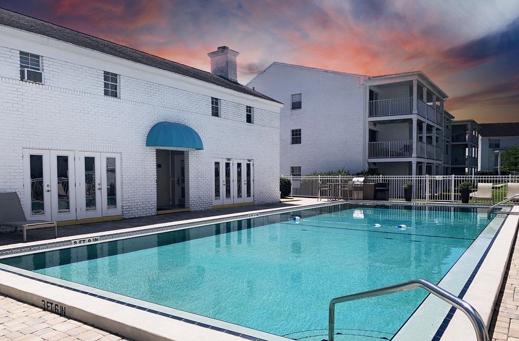 a large swimming pool in front of a white building with a blue awning