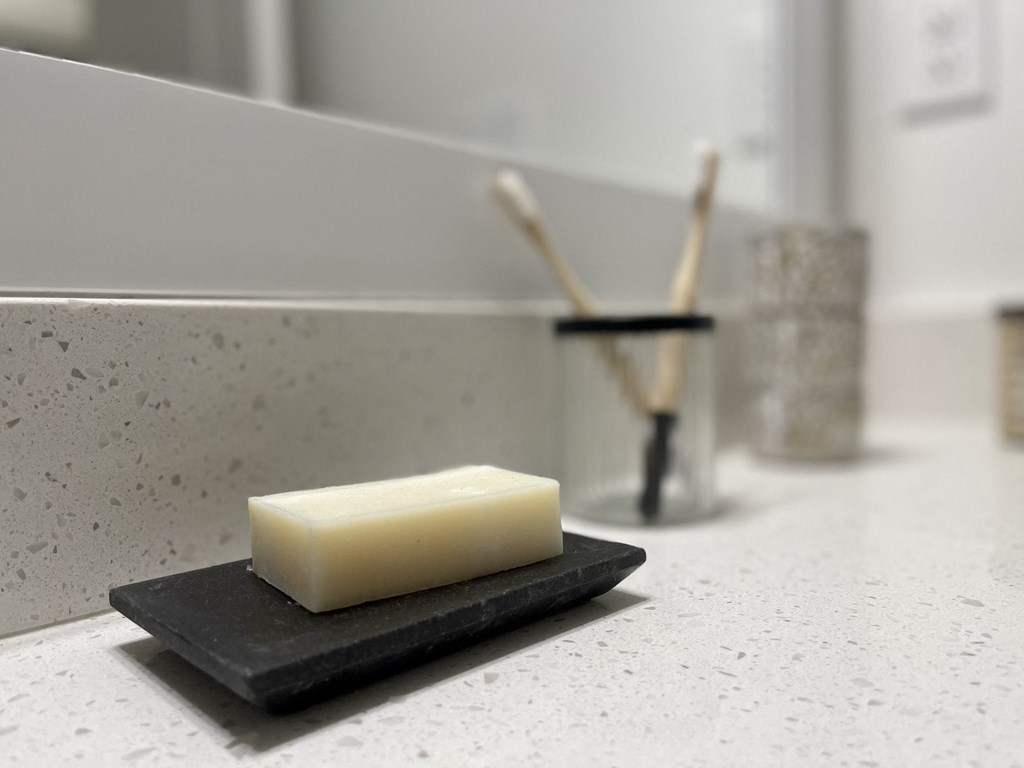 a bar of soap sitting on a black sponge with toothbrushes in the background