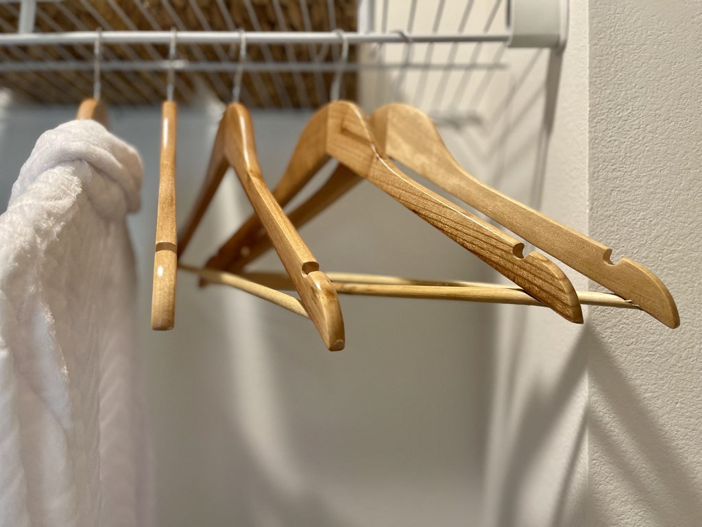 a rack with wooden clothes hangers and a white towel