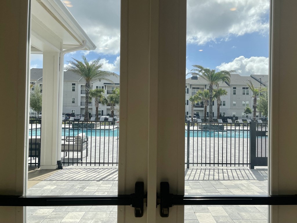 a view of the pool from inside of the clubhouse