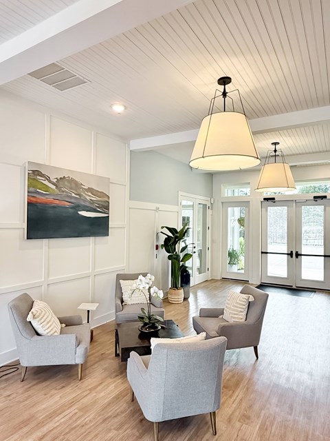 A living room with a grey sofa and a painting on the wall.