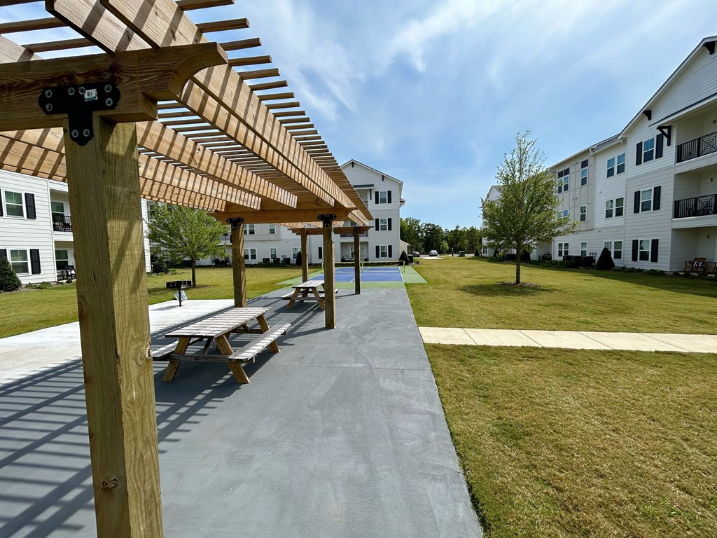 a picnic area with a picnic table and benches in front of an apartment building