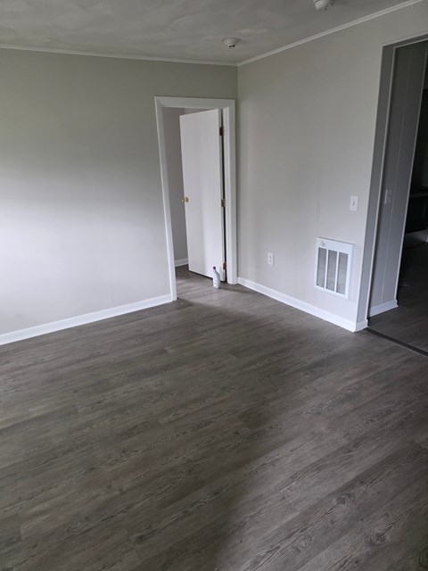 A room with a white door and wood flooring.