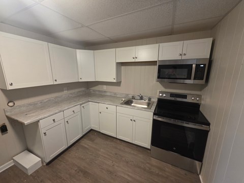 A kitchen with white cabinets and a black stove top oven.