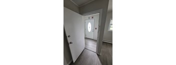 A white door with a round window in the middle is in a room with grey walls.
