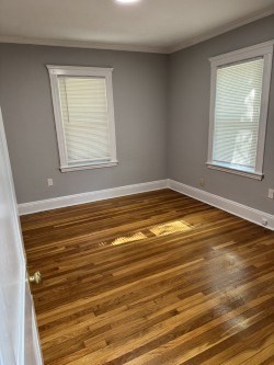 A room with wooden floors and two windows.