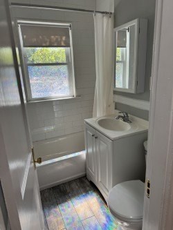 A white bathroom with a toilet, sink, and shower.