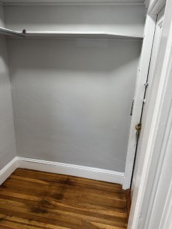 A white door is open to a room with a wooden floor.