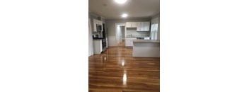 A kitchen with white cabinets and a wooden floor.