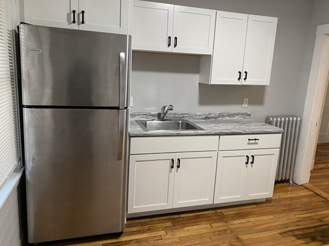 A kitchen with a stainless steel refrigerator and white cabinets.