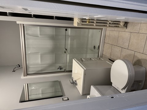 A modern bathroom with a glass shower door and a toilet.
