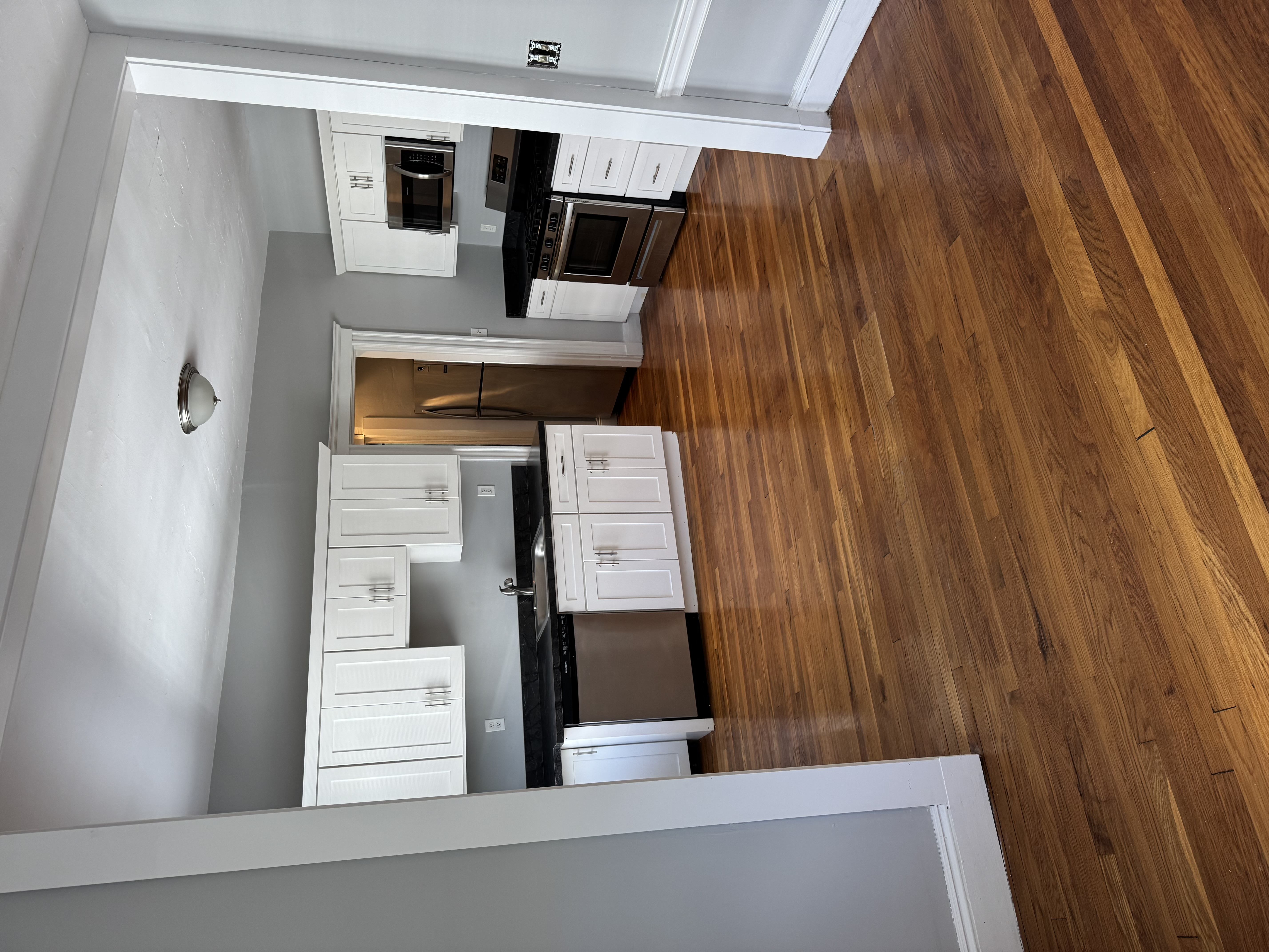 A kitchen with wooden floors and white cabinets.