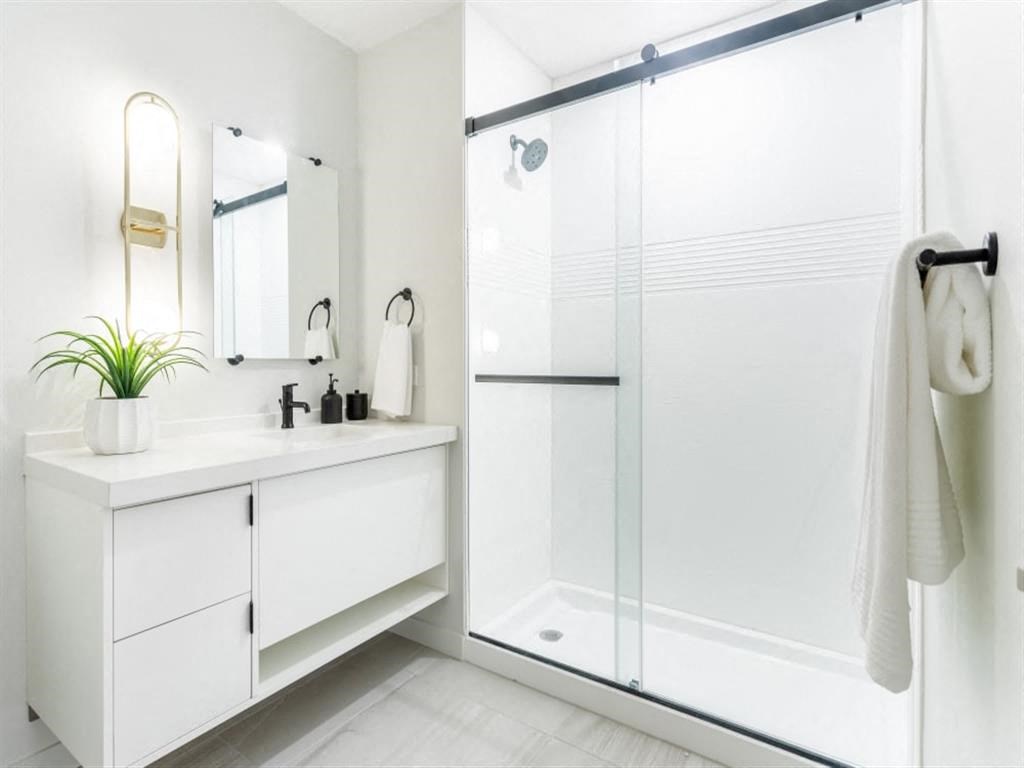a white bathroom with a shower and a sink