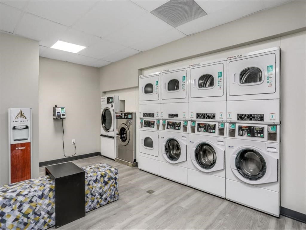 a washer and dryer in a laundry room with a row of washing machines
