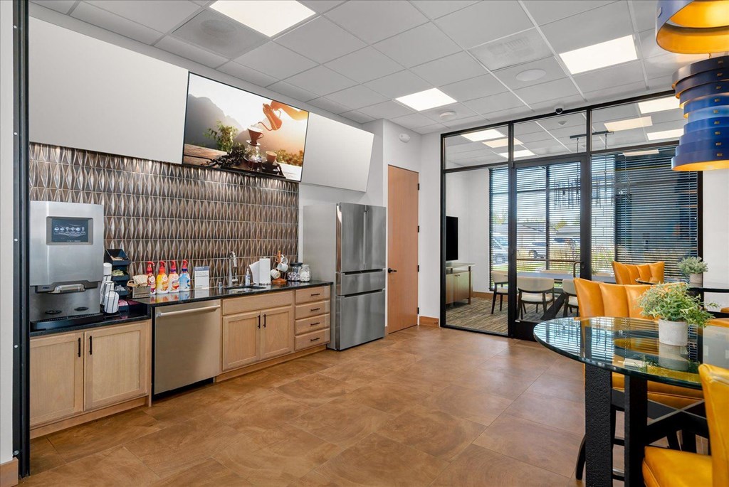 a kitchen and dining area in an office space with a table and chairs