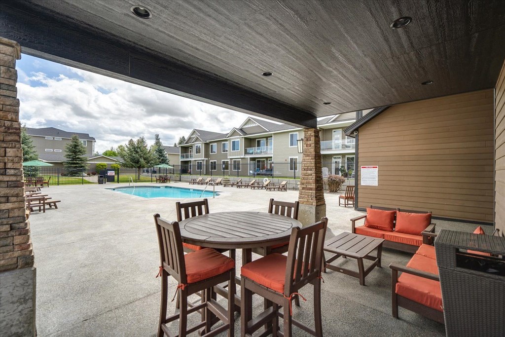 a patio with a table and chairs next to a pool