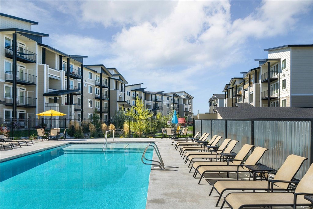 a swimming pool with lounge chairs next to an apartment building