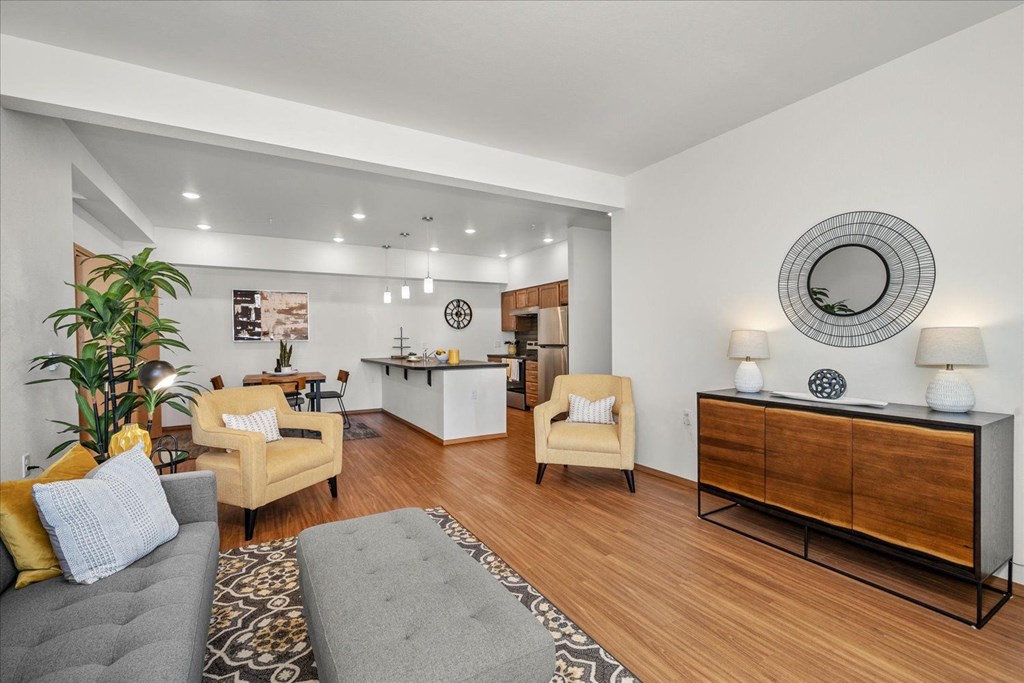 a living room with a couch and chairs and a kitchen