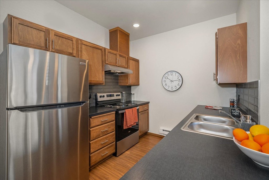 a kitchen with stainless steel appliances and a clock on the wall