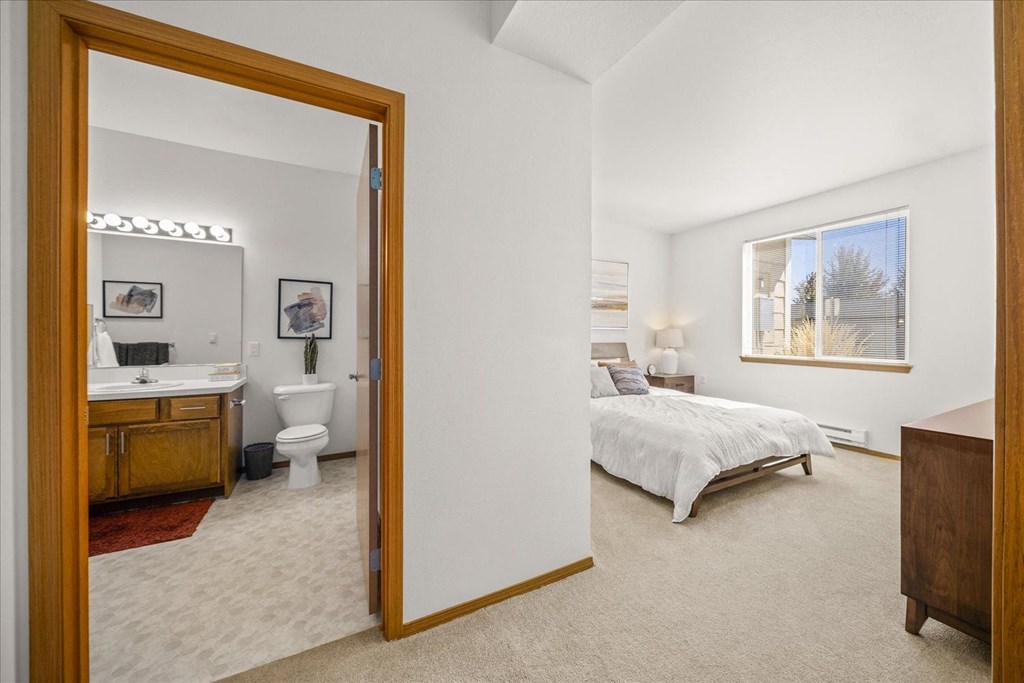 a bedroom with a bathroom and a bed and a mirror