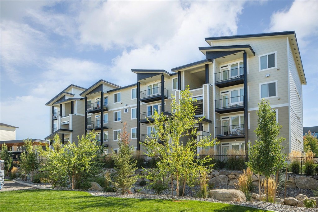a row of apartment buildings with grass and trees