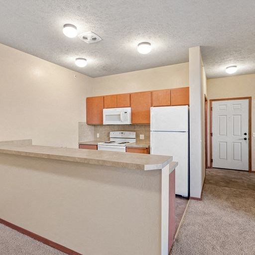 a kitchen with a white refrigerator freezer next to a stove top oven