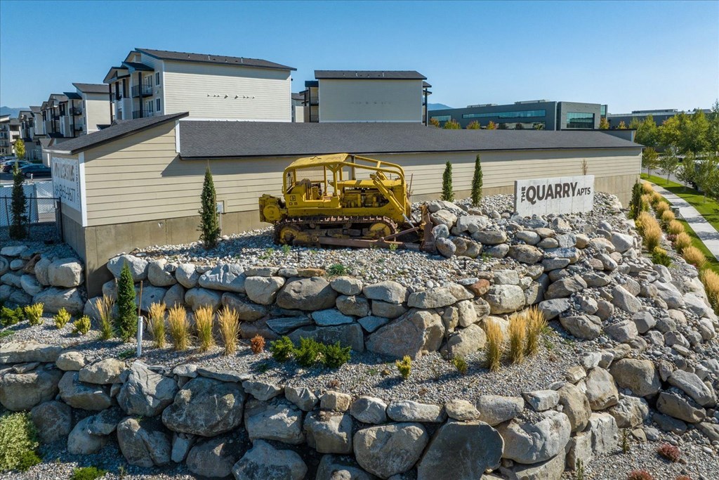 a large rock retaining wall in front of a house with a yellow bulldozer parked