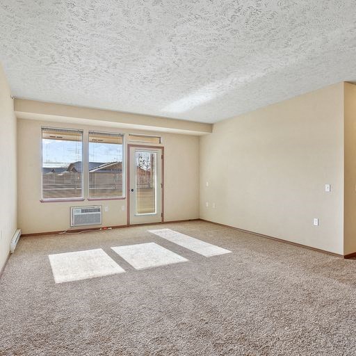 an empty living room with a door and a window