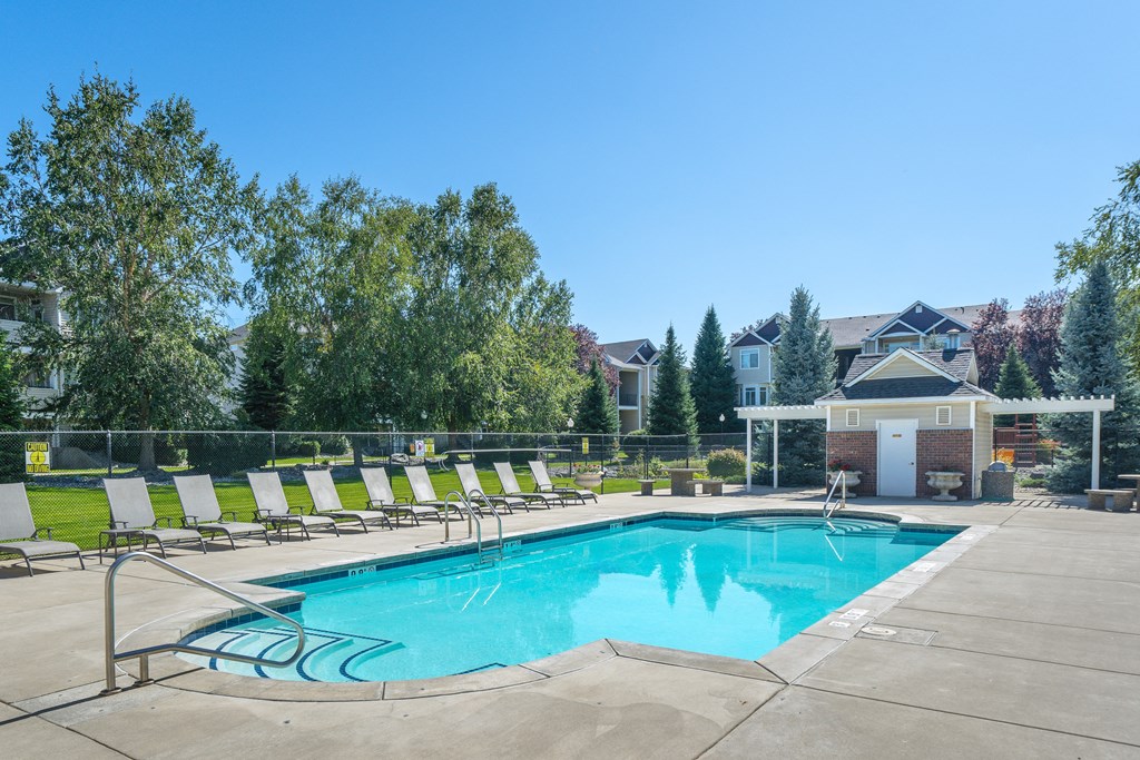 a swimming pool with white chairs around it and a house in the background