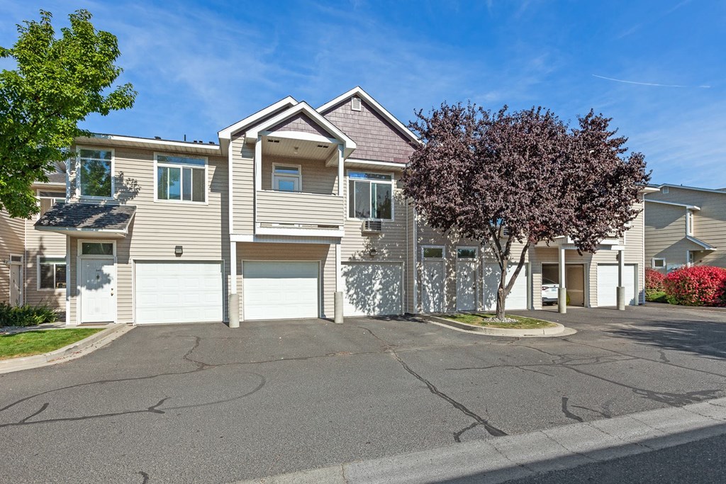 a house with two garages and a tree in front of it