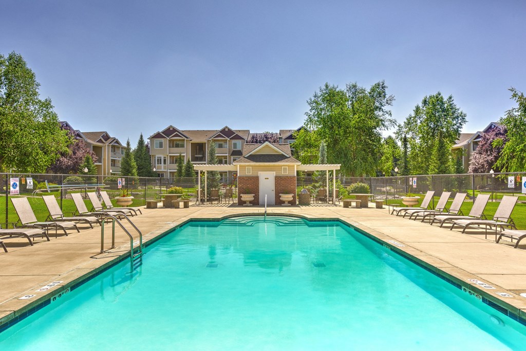 a swimming pool with chaise lounge chairs and trees in the background