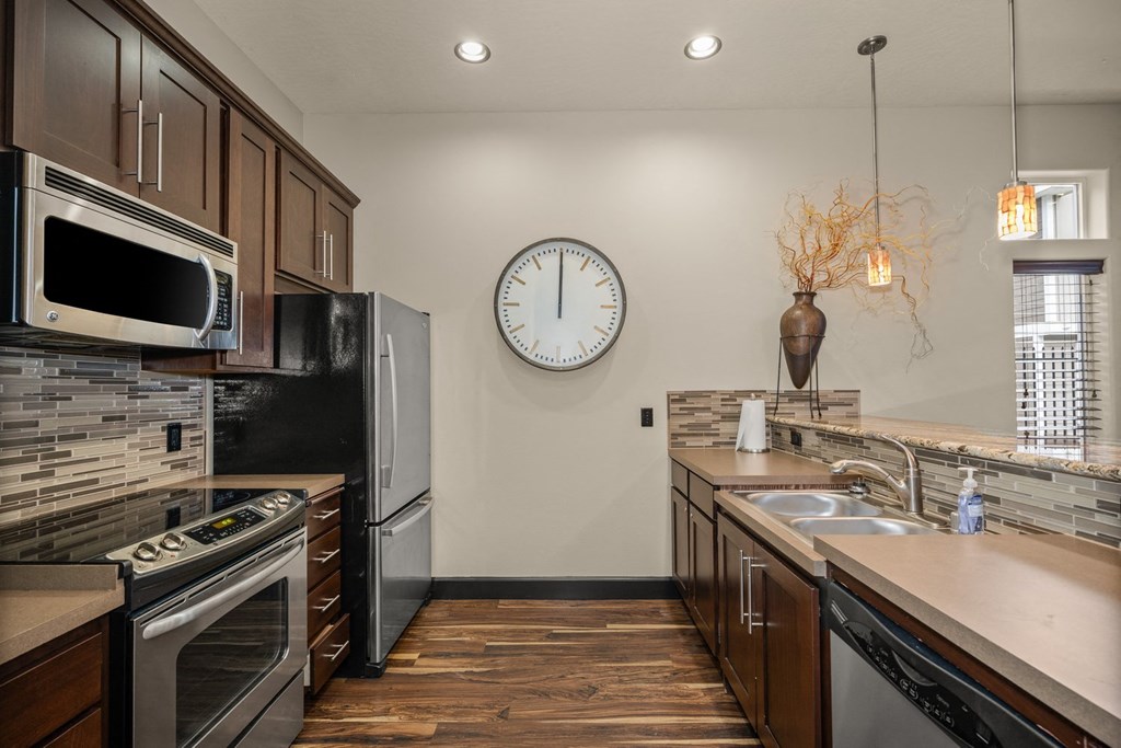 a kitchen with stainless steel appliances and a clock on the wall