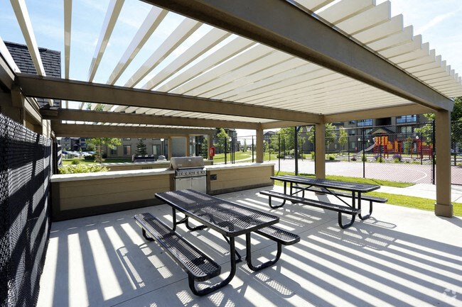 A picnic area with a grill and picnic table in front of a building
